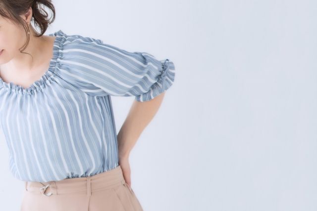 腰に痛みを感じる女性